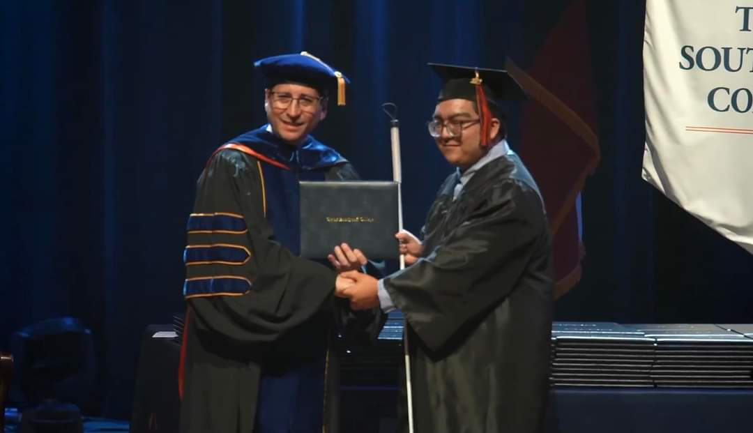 Photo shows Erik at a graduation ceremony receiving a diploma.