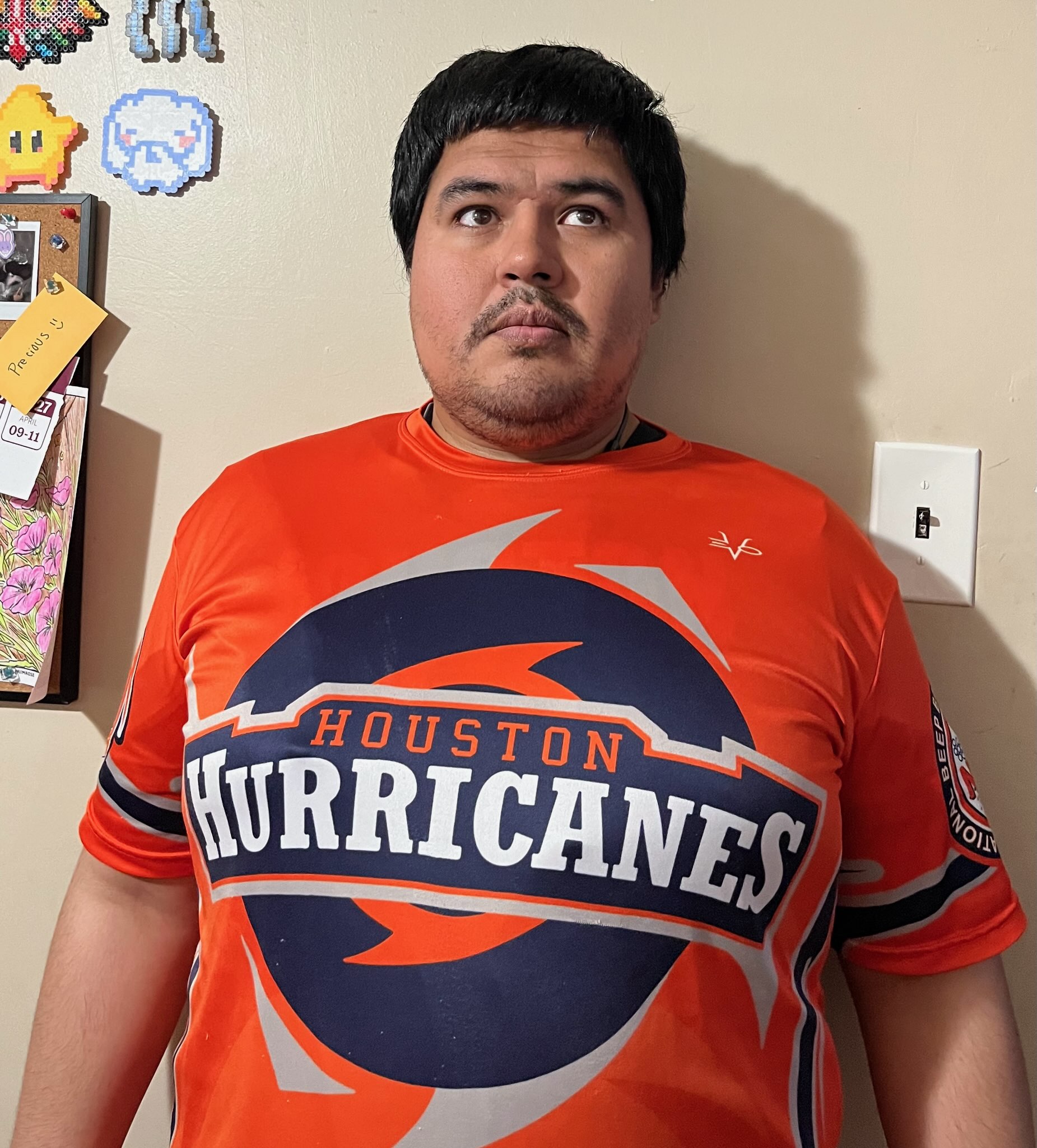 Juan Carlos stands, wearing his orange and blue Houston Hurricanes jersey